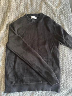 Mörkgrå stickad tröja Selected Homme - Säljer en stilren mörkgrå stickad tröja från Selected Homme. Tröjan har rund halsringning, ribbade muddar vid ärmslut och nederkant samt en diskret struktur i materialet. Perfekt basplagg för lager på lager och enkel att matcha.