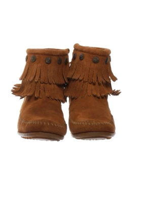 Bruna mocka boots med fransar - Säljer ett par bruna boots i mocka med dubbla lager fransar och dekorativa metallknappar runt skaftet. Bootsens sula är platt och sydd med synliga sömmar. Perfekta för dig som gillar en boho eller western-inspirerad stil.