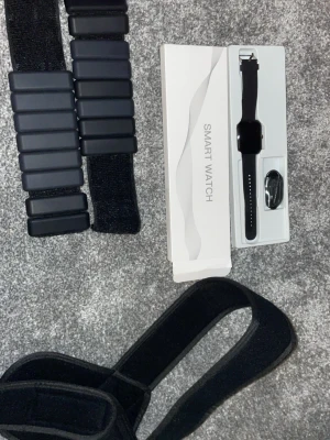 Svart smartwatch - Snygg svart smartklocka med rektangulär display och silikonarmband. Kommer i originalförpackning med laddkabel. Modern design som passar till det mesta och har flera smarta funktioner. Perfekt för dig som vill ha koll på notiser och hälsa direkt på handleden.