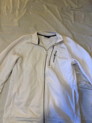 Vit ziptröja från Sail Racing - Vit ziptröja från Sail Racing med  logga på bröstet och dragkedja framtill. Tröjan har krage och en bröstficka. Knappt använd, storlek S - pris kan diskuteras 