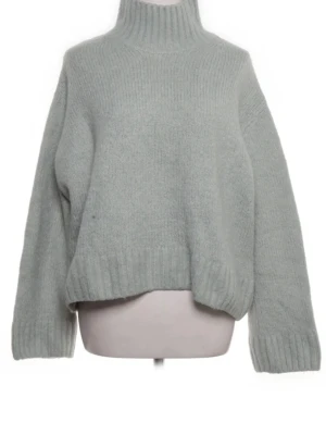Ljusgrön stickad polotröja - Mysig ljusgrön stickad polotröja med avslappnad passform och ribbade muddar vid ärmslut och nederkant. Tröjan har hög krage och är perfekt för kyliga dagar. Materialet känns mjukt och värmande.