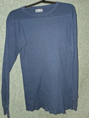 Mörkblå långärmad tröja Deauville - Mörkblå långärmad tröja från Deauville i ribbad bomullsmix. Tröjan har rund halsringning och en enkel, stilren design som passar perfekt till jeans eller under en jacka. Lätt stretchigt material för extra komfort. Är öppen för prisförslag vid snabb försäljning.