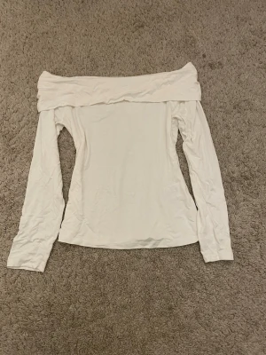 Vit offshoulder topp Molly M - Trendig vit offshoulder topp från Molly i storlek M. Toppen har långa ärmar och en bred kant över axlarna som ger en snygg och modern look. Perfekt att styla med jeans eller kjol för en clean och fräsch outfit.