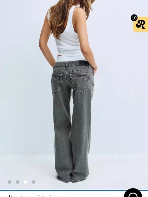 Gråa ultra low wide jeans - Säljer ett par gråa ultra low wide jeans med riktigt lös passform och låg midja. Jeansen har klassiska fem fickor och slitna detaljer för en cool vintagekänsla. Perfekta för dig som gillar avslappnad streetstil.