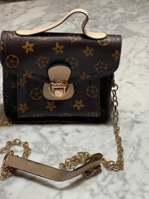 Brun liten axelremsväska i nyskick - Brun liten axelremsväska i nyskick. 