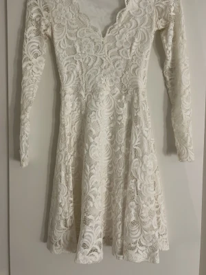 Vit spetsklänning med v-ringning - Superfin vit kortklänning i spets med v-ringad hals och långa ärmar. Den är från bubbleroom, i storlek xxs.