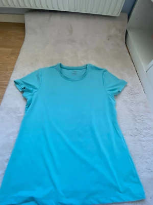 Turkos basic t-shirt i bomull - Enkel och fräsch turkos t-shirt med rund hals och korta ärmar. Tillverkad i mjuk bomull som känns skön mot huden. Perfekt till jeans eller shorts för en avslappnad look. men funkar även till träning!