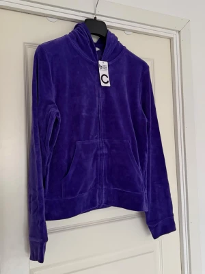 Lila velour hoodie från Cubus - Säljer en lila hoodie i mjuk velour från Cubus. Hoodien har dragkedja framtill, känguruficka och en skön huva. Perfekt för dig som gillar en chill och trendig stil. Materialet är lent och ger en lyxig känsla. Märkt med storlek M.