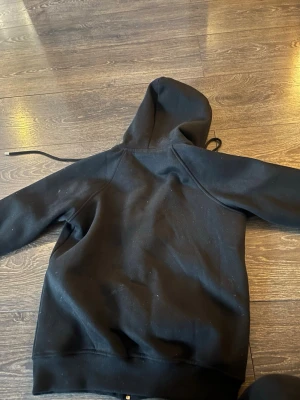 Svart hoodie från Burberry - Snygg svart hoodie från Burberry med dragkedja och klassiskt rutigt foder i huvan. Tillverkad i mjukt bomullsmaterial och har snörning i huvan. Perfekt för en chill och stilren look.