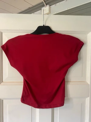 Röd croppad topp med öppen rygg - Snygg röd croppad topp i mjukt material med korta ärmar och en stor öppen rygg. Perfekt för dig som vill ha en enkel men ändå statement topp till din outfit. Passar till både jeans och kjol.