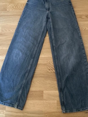 Blåa wide leg jeans - Säljer ett par trendiga blåa wide leg jeans med hög midja och raka, vida ben. Jeansen har klassisk femficksdesign och är tillverkade i denim. Perfekta för en avslappnad och cool stil.