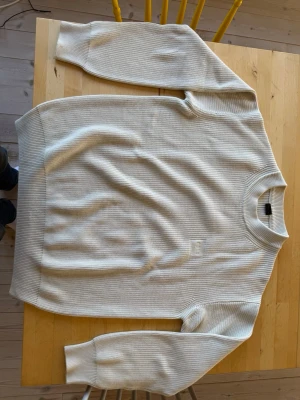 Vit ribbstickad tröja från Hugo Boss - Säljer denna ribbstickade Hugo Boss tröjan då den aldrig kom till stor användning för mig. Den är stilren är ett bra basplagg. Den är i nyskick då den knappt blivit använd men har ej kvitto eller prislapp kvar. Priset är ej spikat.