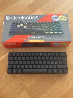 SteelSeries Apex 9 Mini tangentbord/RAPID TRIGGER - Säljer ett SteelSeries Apex 9 Mini gamingtangentbord i kompakt 60% format. Tangentbordet är svart med optiska switchar och RGB-belysning. Perfekt för gaming och tar minimalt med plats på skrivbordet. Levereras i originalkartong.