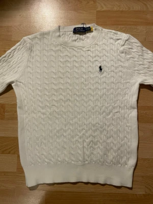 Vit kabelstickad tröja Polo Ralph Lauren - Vit kabelstickad tröja från Ralph Lauren.   Helt ny och aldrig använd.  Är storlek M, men upplevs som något mindre (mer som S i passformen).  Klassisk och stilren modell som passar till det mesta.  Hör av dig om du har frågor! 😃