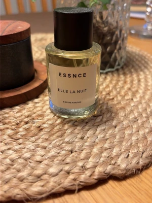 ESSNCE Elle La Nuit Eau de Parfum - En stilren parfym från ESSNCE med namnet Elle La Nuit. Flaskan är cylindrisk i genomskinligt glas med svart lock och enkel vit etikett. Innehållet är ljust gult och ger en exklusiv känsla. Perfekt för dig som gillar minimalistisk design. 