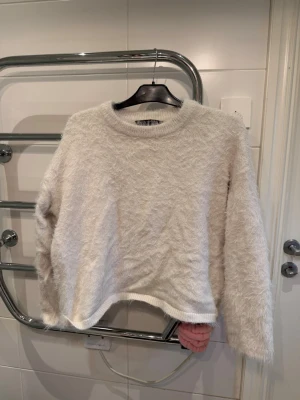 Vit fluffig stickad tröja Pernilla Wahlgren - Mysig vit stickad tröja från Pernilla Wahlgren Design. Tröjan har en fluffig, lurvig textur och rund halsringning. Perfekt för kalla dagar när du vill vara både varm och snygg. Långärmad och med avslappnad passform.