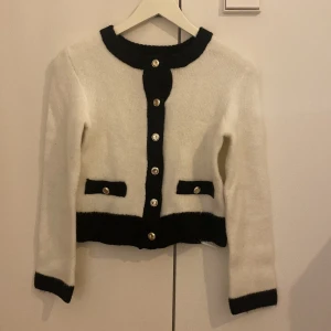 Vit och svart kofta från Amisu  - Snygg vit kofta från Amisu med svarta detaljer vid krage, knappslå, fickor, ärmslut och nederkant. Silverknappar framtill. Storlek XS🤍🖤 