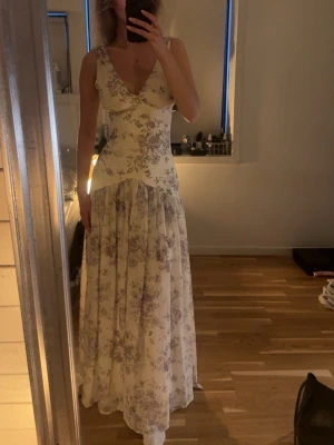 Lång blommig klänning med v-ringning - Jättefin klänning från Adoore men aldrig kommit till användning. Storlek 34