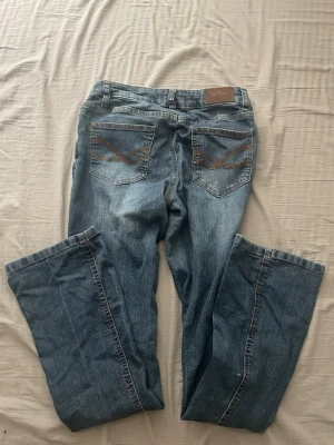 Blå bootcut jeans från John Baner - Säljer ett par klassiska blå bootcut jeans från John Baner. De är lågmidjade. Jeansen har snygga broderade detaljer på bakfickorna. Tillverkade i slitstark denim med en skön passform. Perfekta till vardagslooken! Köpte av en annan och storlekslappen är bortklippt men skulle säga att de är ca storlek S. 