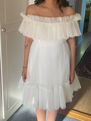 Vit offshoulder kortklänning brud/studentklänning från ByMalina - Säljer en superfin vit offshoulder klänning med volangdetaljer och plisserad kjol. Klänningen är ifrån ByMalina i super fint skick enbart använd på studentdagen, men tvättad efter. Strl XS, men skulle säga att den passar XS till Liten M. Perfekt som studentklänning eller brudklänning. 🌸