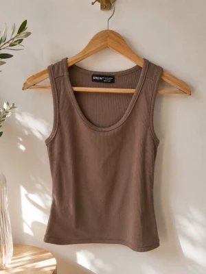 Brun ribbad linnetopp från SHEIN - Säljer en brun ribbad linnetopp från SHEIN i storlek L. Toppen är ärmlös med rund halsringning och har en tight passform. Perfekt att styla till jeans eller kjol för en enkel och snygg look.