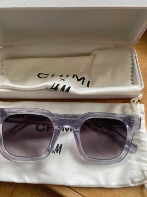 Ljuslila CHIMI x H&M solglasögon - Snygga solglasögon från CHIMI x H&M med transparent ljuslila bågar och rektangulär form. Glasen är mörka och ger en cool kontrast till den ljusa bågen. Kommer med originalfodral och putsduk.