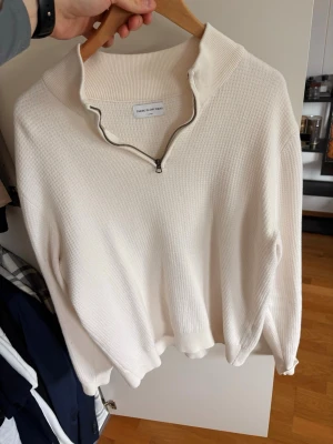  halvzip  These glory Days - Snygg vit stickad tröja från These glory Days med halvzip och hög krage. Tröjan har en avslappnad passform, ribbade muddar och är tillverkad i ett mjukt material. Perfekt för lager på lager och enkel att styla till olika outfits.