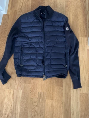 Mörkblå cardiganjacka från Moncler - Snygg mörkblå cardiganjacka från Moncler med quiltad framsida och stickade ärmar.  den har inga skador använd i några månader står m men skulle säga passar mig som är xs och s men kan passa m också beror på din längd o vikt pris kan diskuteras och tar byten beror på vad det är den är mörkblå