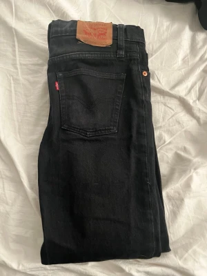 Svarta Levi's jeans 501 - Säljer ett par svarta jeans från Levi's med passformen slim. Jeansen har Levi's ikoniska läderpatch bak i midjan och röd logotagg på bakfickan. Tillverkade i slitstarkt denimtyg, perfekta till alla tillfällen.