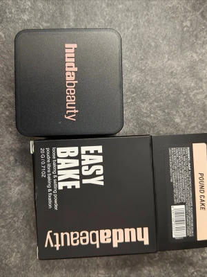 Huda Beauty Easy Bake Pound Cake - Loose setting powder från Huda Beauty i nyansen Pound Cake. Kommer i en fyrkantig svart burk med skruvlock och tillhörande kartong. Pudret är ljust beige och ger en matt finish, perfekt för att fixera foundation och ge en jämn look. OÖPPNAD!!