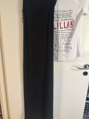 Svart långklänning från Gina Tricot - En stilren svart långklänning från Gina Tricot. Klänningen har en enkel och rak passform, är ärmlös och tillverkad i ett mjukt och stretchigt material som känns bekvämt mot huden. Perfekt för dig som gillar minimalistisk stil.