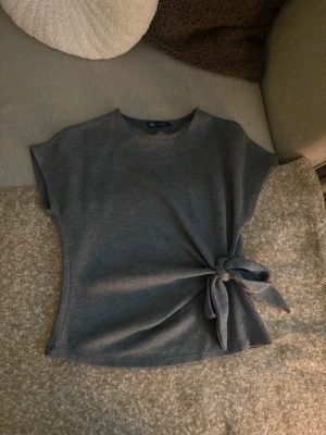 Grå topp med knyt från Zara - Jättesnygg topp från Zara som knappt är använd 