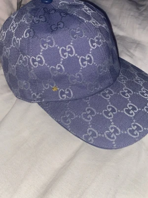 Blå keps - Säljer en blå keps. Kepsen har böjd skärm och är tillverkad i ett slitstarkt tyg med vit insida. Perfekt för dig som vill ha en stilren och lyxig accessoar.