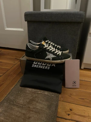 Golden Goose skor - Mörkgröna sneakers från Golden Goose med vit sula, vita skosnören och en silverglittrig stjärna på sidan. Skorna har en låg profil och detaljer i mocka samt en gul etikett på plösen. Perfekta för dig som gillar en unik och trendig look. Box, dustbag medföljer 