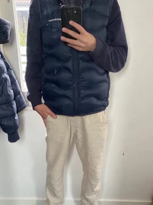 Mörkblå dunväst från Peak Performance - Snygg mörkblå dunväst från Peak Performance. Den är typ helt oanvänd och den är använd max en vecka. Den är lite för liten för mig och den har storlek 160 och jag är 175 så den skulle passa dig om du är runt 160-172 cm lång. Den har inga slitningar alls och inga hål heller. Den är köpt nypris 1999 från Peaks affär.
