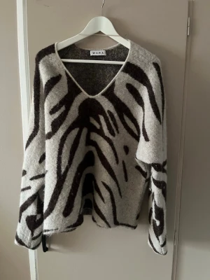 Zebramönstrad stickad tröja Wera - Säljer en stickad tröja från Wera i alpackamix med zebramönster i svart och beige.  