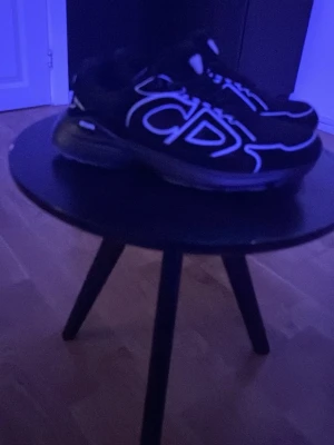 Svarta Dior B30 sneaker med vita detaljer - Säljer ett par svarta Dior sneakers med tydliga vita kontrastdetaljer och CD-logga på sidan. Skorna är helt oandvända, har box och dustbag 