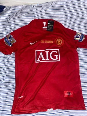 Manchester United Ronaldo tröja Nike - Säljer en röd Manchester United matchtröja från Nike med Ronaldo och nummer 7 på ryggen. Tröjan har vita detaljer, klubbmärke och Premier League-märke på ärmen. Tillverkad i lätt och ventilerande material med NikeFITDRY-teknologi.