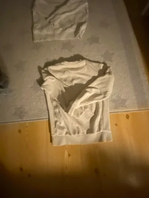 Vit kabelstickad tröja - Säljer en vit kabelstickad tröja med rund hals och ribbade muddar. Tröjan har ett klassiskt mönster och är perfekt för att hålla värmen under kyliga dagar. Passar till både jeans och kjol för en clean look. För båda 