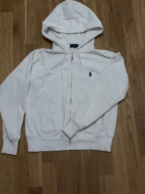 Vit zip hoodie från Polo Ralph Lauren - Säljer en vit hoodie med dragkedja från Polo Ralph Lauren. Köptes för 1148kr ifrån Zalando. Kvitto finns! Mycket bra skick på den. Perfekt för en avslappnad och stilren look.