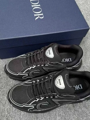 Svarta Dior sneakers med vita detaljer - Snygga svarta Dior sneakers med vita kontrastdetaljer och logga på plösen. Skorna har en sportig design med mesh och syntetmaterial, samt svarta skosnören. Perfekta för dig som vill ha en trendig och exklusiv look.