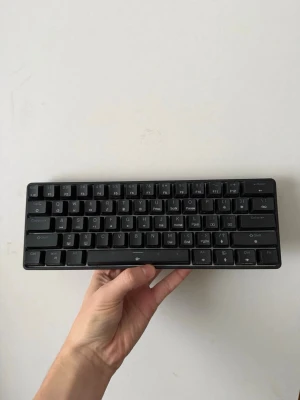 Svart mekaniskt tangentbord DK61SE - Säljer ett kompakt svart mekaniskt tangentbord, modell DK61SE från Royal Kludge. Tangentbordet har 61 tangenter och en stilren design med svarta plasttangenter och chassi. Perfekt för dig som vill ha ett smidigt och portabelt tangentbord till datorn. Röda Switches 