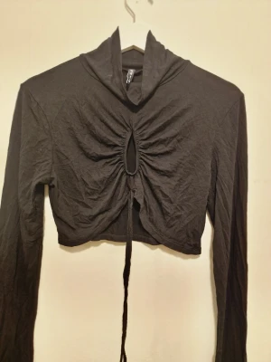 Svart långärmad cropped topp - Svart crop top med dragsko framtill som ger en rynkad effekt.