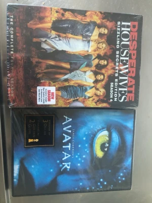 Desperate Housewives S4 & Avatar DVD - Två DVD-boxar: Desperate Housewives Säsong 4 Sizzling Secrets Edition med färgstarkt omslag och Avatar av James Cameron med blått, detaljrikt omslag och ikoniskt öga. Perfekt för film- och seriemaraton hemma.    Oöppnad inplastade 
