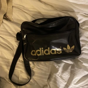 Supersnygg Adidasväska  - Trendig svart-guldig adidasväska. Passar perfekt till skolan då den platsar en dator. Möts upp i Stockholm eller fraktar☺️