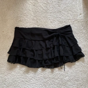 Lågmidjad kjol  - Så fin lågmidjad volangkjol! Dragkedja på sidan och även en knytning på andra sidan 🖤 Helt oanvänd! 