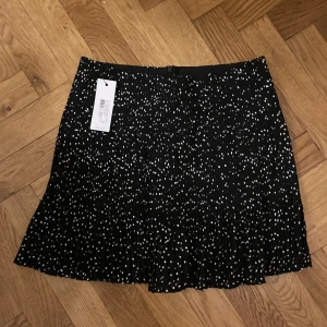 Prickig veckad kjol, ENVII - Storlek:S Söt svart veckad kjol med vita prickar.  Helt ny med prislappen kvar.  Nypris 470 NOK.   Säljs pga använder sällan kjol. 