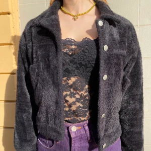 Svart fluffig jacka - Fluffig svart jacka med silvriga knappar. Den är jättemjuk och varm. Jag har använt den förra vintern och våren. Den har bra kvalitet. Den är perfekt i armarna och jag är 1,70cm. Den har ett litet hål under kragen som inte syns. 
