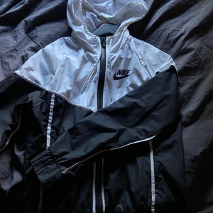 Nike jacka - Svart-vit Nike vindjacka. Är använd men bra skick, sminkfläckarna tvättas bort innan köp såklart💓 Nypris runt 800-900 tror jag men säljer för 300, pris kan diskuteras💕