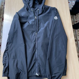 Moncler regnjacka - Moncler regnjacka till salu, svart förg och storlek 3. Tunt vattentät matrial men hög kvalite. Den är i nyskick. Har NFC.  Funderingar? Skriv görna så svarar jag
